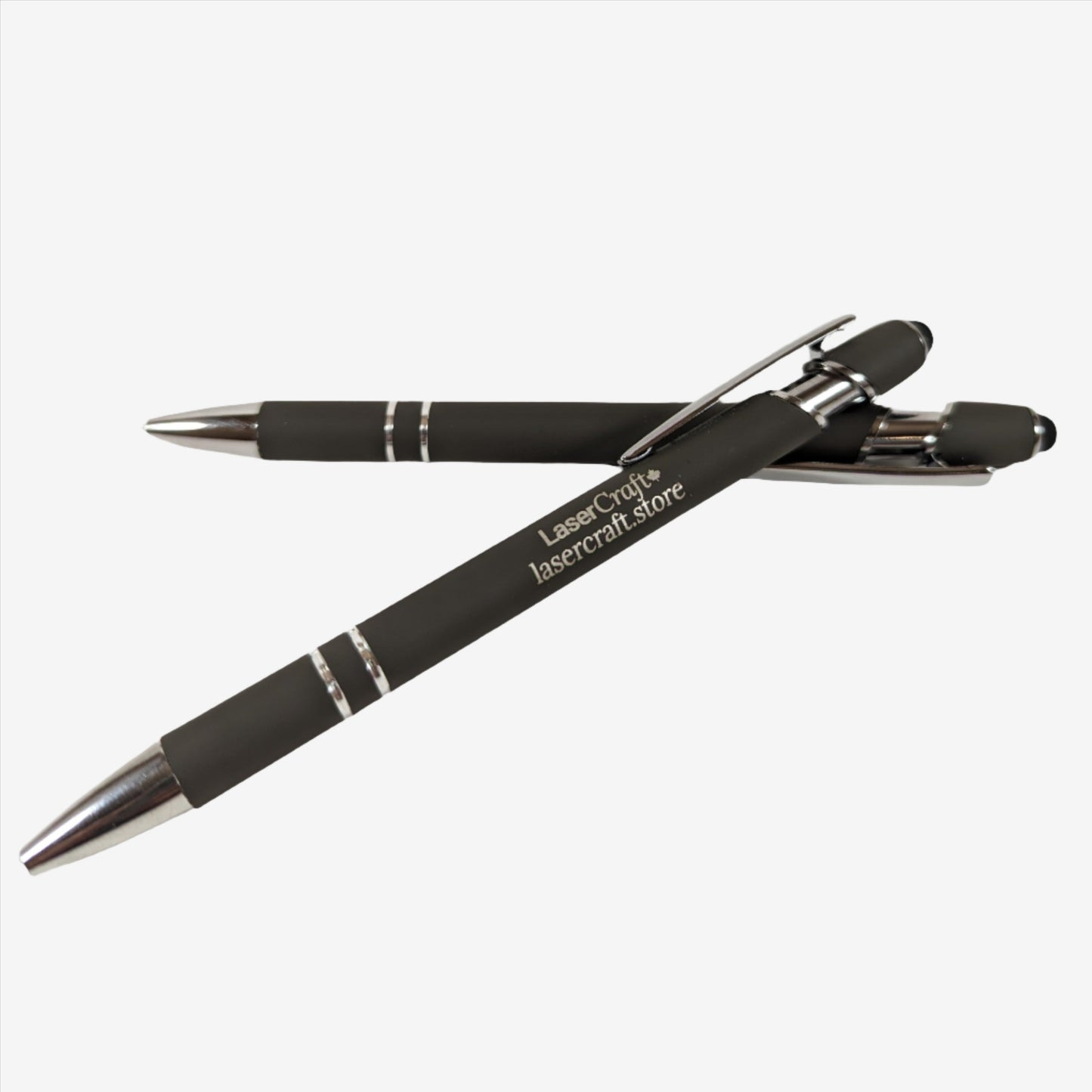 Two dark gray pens with custom laser engraving displayed. The pens are sleek and elegant, featuring precise, silver-colored engravings along their barrels, showcasing the personalization option available.