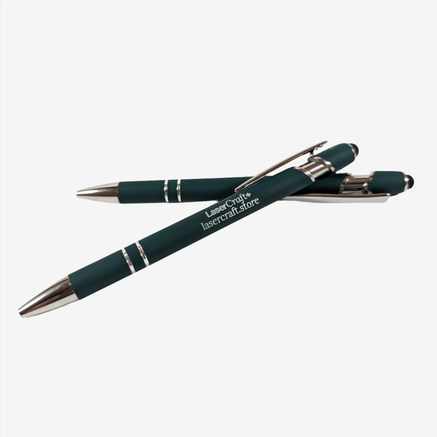 Two dark green pens with custom laser engraving displayed. The pens are sleek and elegant, featuring precise, silver-colored engravings along their barrels, showcasing the personalization option available.