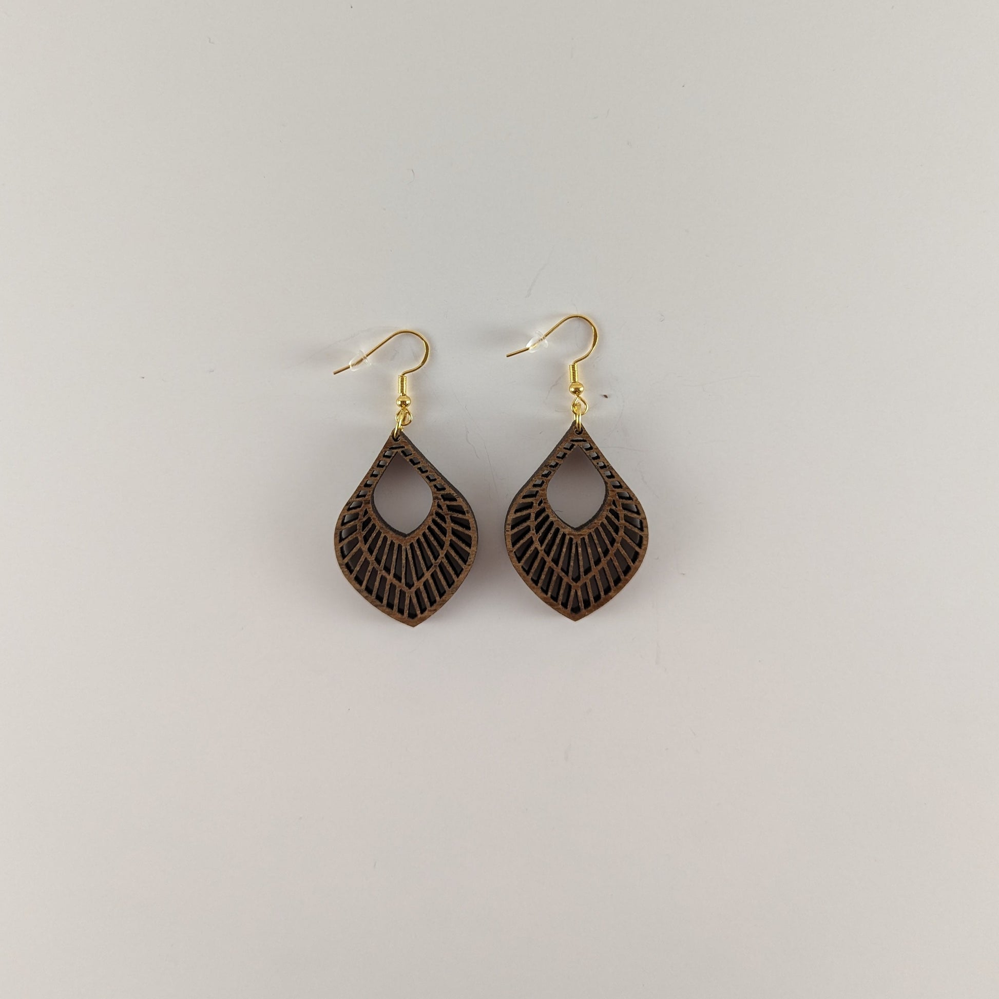 Handcrafted teak earrings featuring intricate laser-engraved designs, showcasing natural wood grain and artistic detailing. They feature a beautiful petal design.