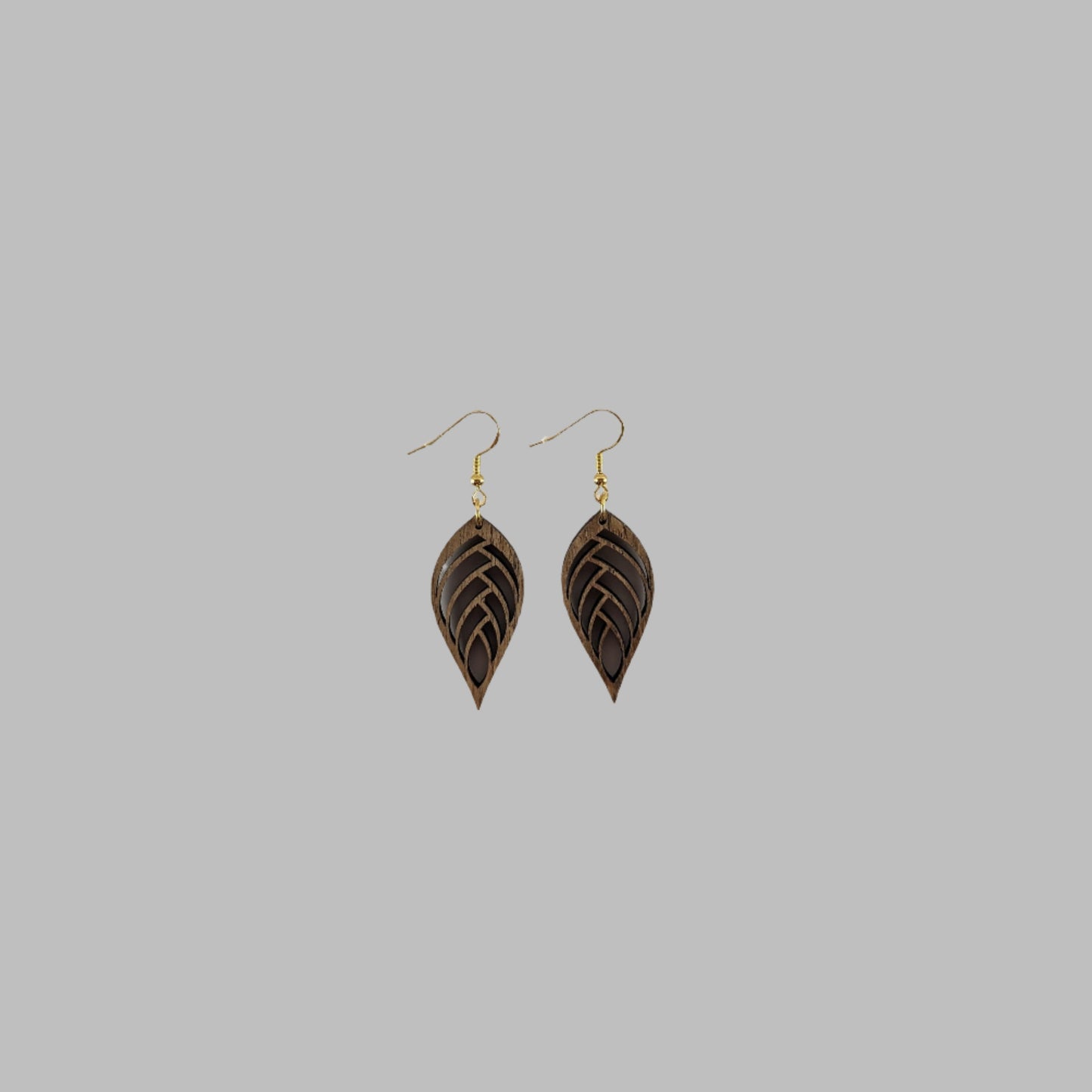 Handcrafted teak earrings featuring intricate laser-engraved designs, showcasing natural wood grain and artistic detailing. They feature a beautiful leaf design.