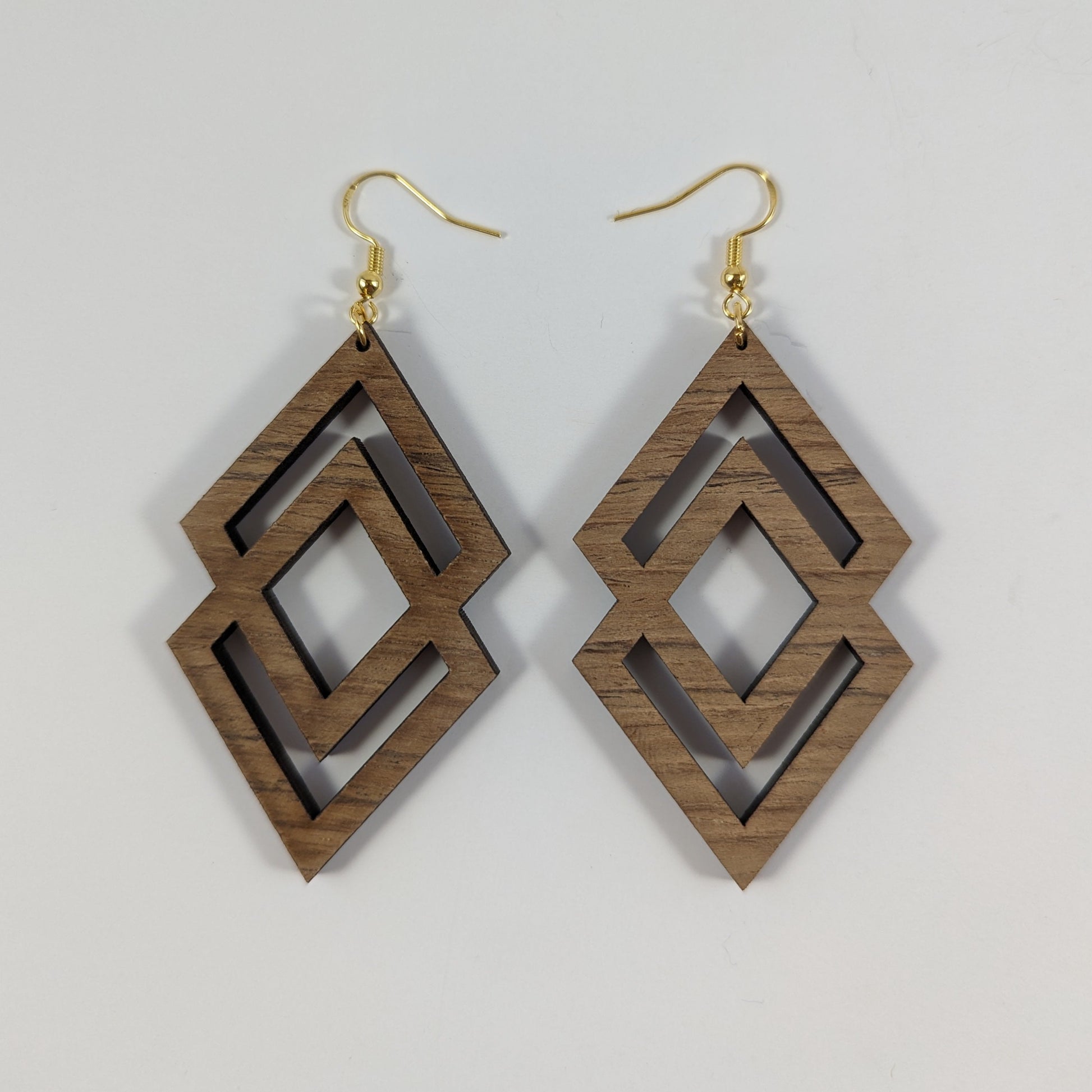 Handcrafted teak earrings featuring intricate laser-engraved designs, showcasing natural wood grain and artistic detailing. They feature a beautiful diamond design.