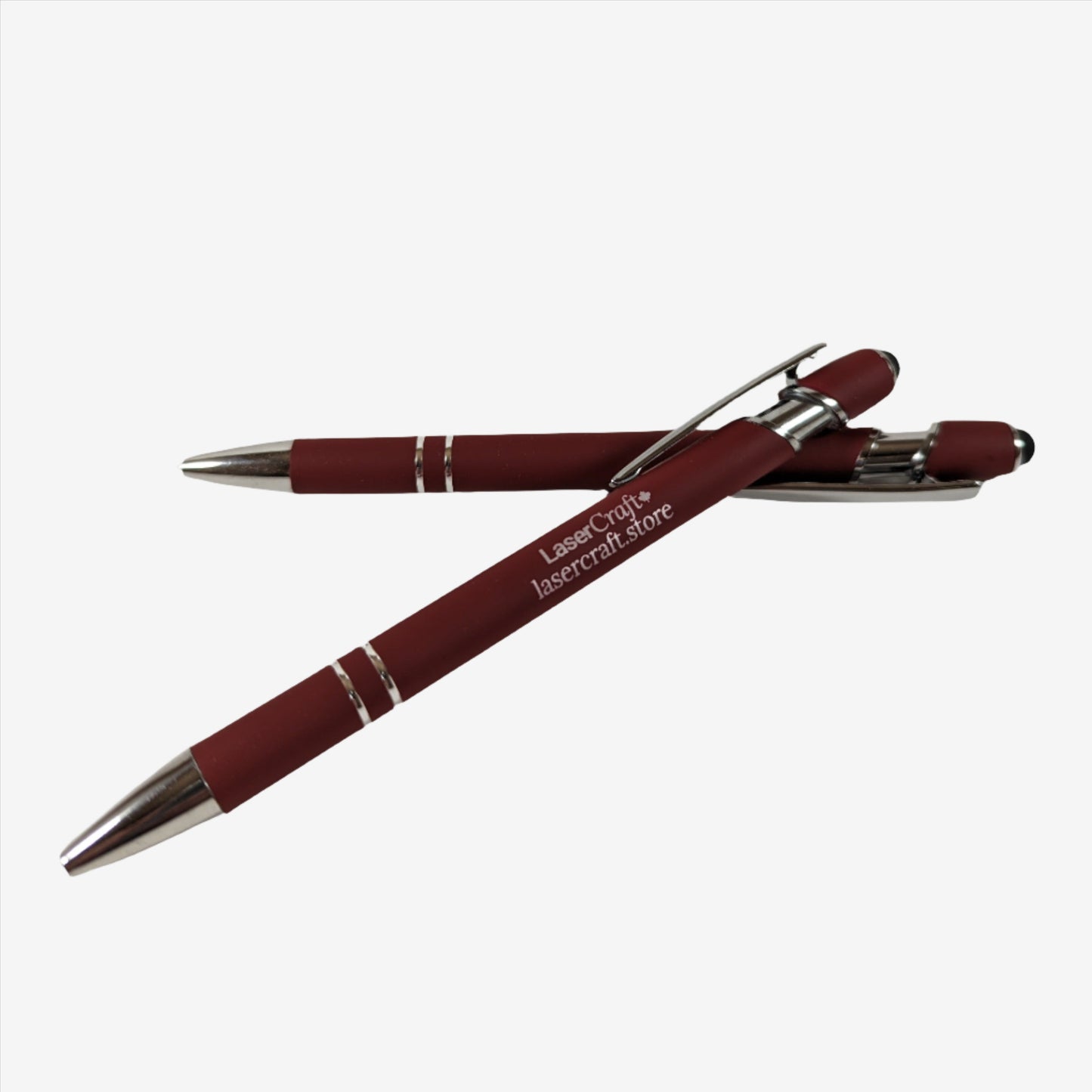 Two dark red pens with custom laser engraving displayed. The pens are sleek and elegant, featuring precise, silver-colored engravings along their barrels, showcasing the personalization option available.